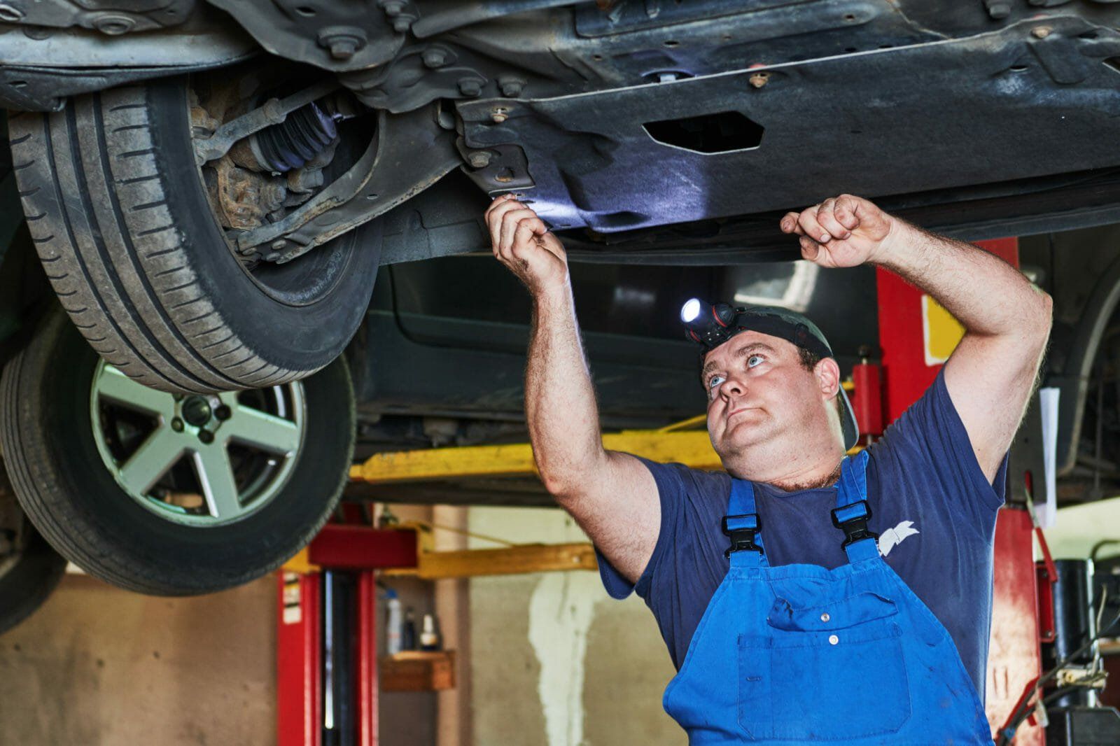 Automobile mechanic checks car suspension in service station