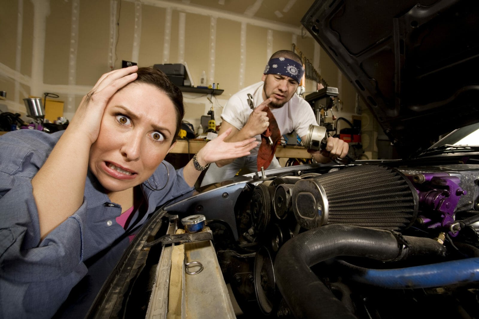 Frustrated woman with incompetent mechanic in background